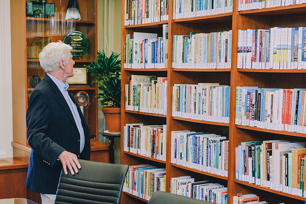 Lester R. Brown looking at books on shelves in the Lester R. Brown Reading Room.